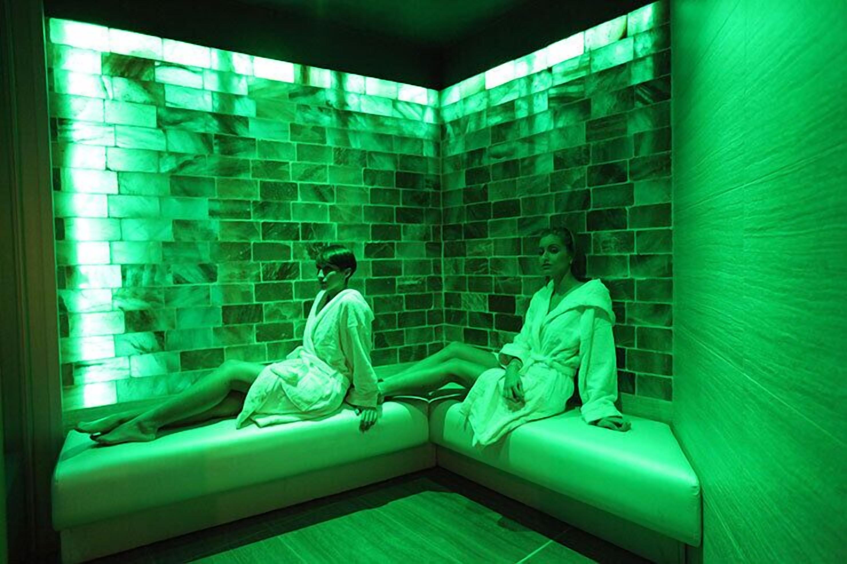 Una habitación con dos sillones reclinables, un muro de azulejos y suelo de madera.