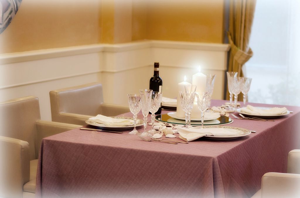 A table set for dining with a bottle of wine, multiple glasses, and plates.