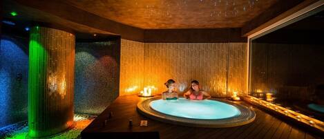 Wellnessbereich mit Whirlpool, Holzboden und Wand mit vertikalen Linien.