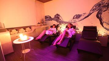 Una habitación con cuatro sillones reclinables, una mesita con una vela y un mural en la pared.