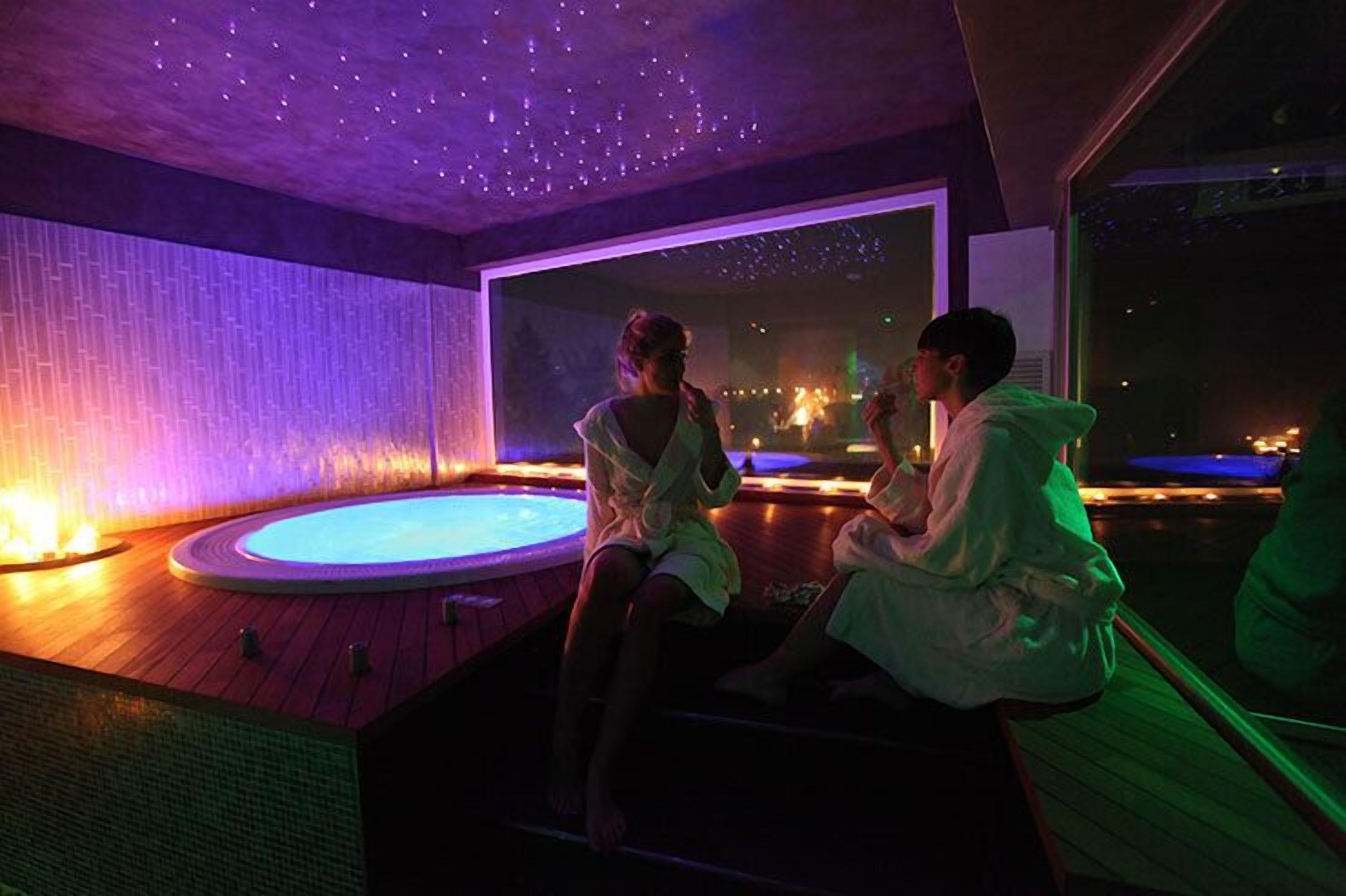 Ein Paar entspannt in einer Hot Tub mit Blick auf die Stadt, unter einem Sternenhimmel.