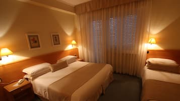 A hotel room with two beds, a nightstand with a phone, and two wall-mounted lamps.