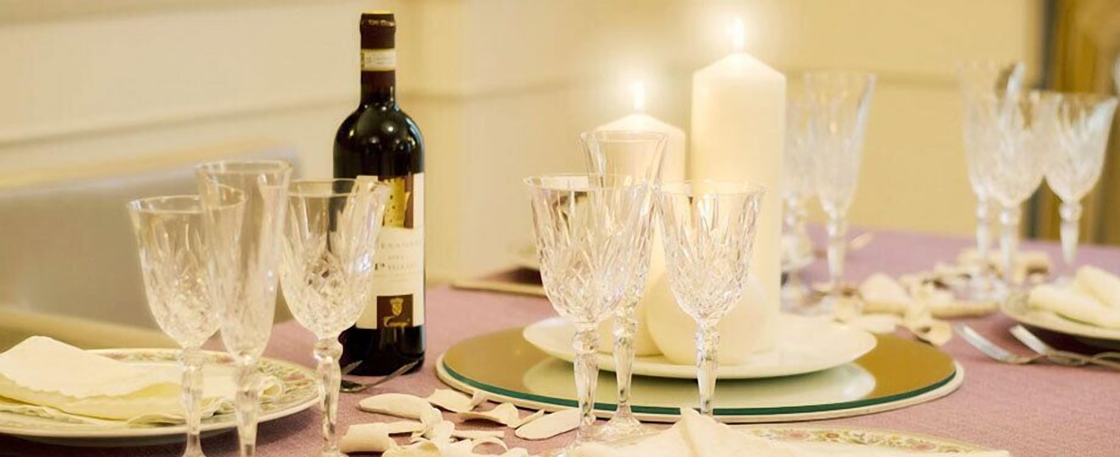A table set with crystal glasses, a bottle of wine, and a candle.