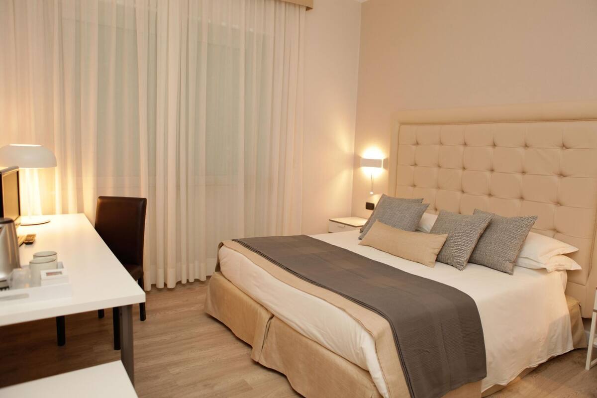 Une chambre d’hôtel comprenant un lit, des tables de chevet, un bureau et une chaise.