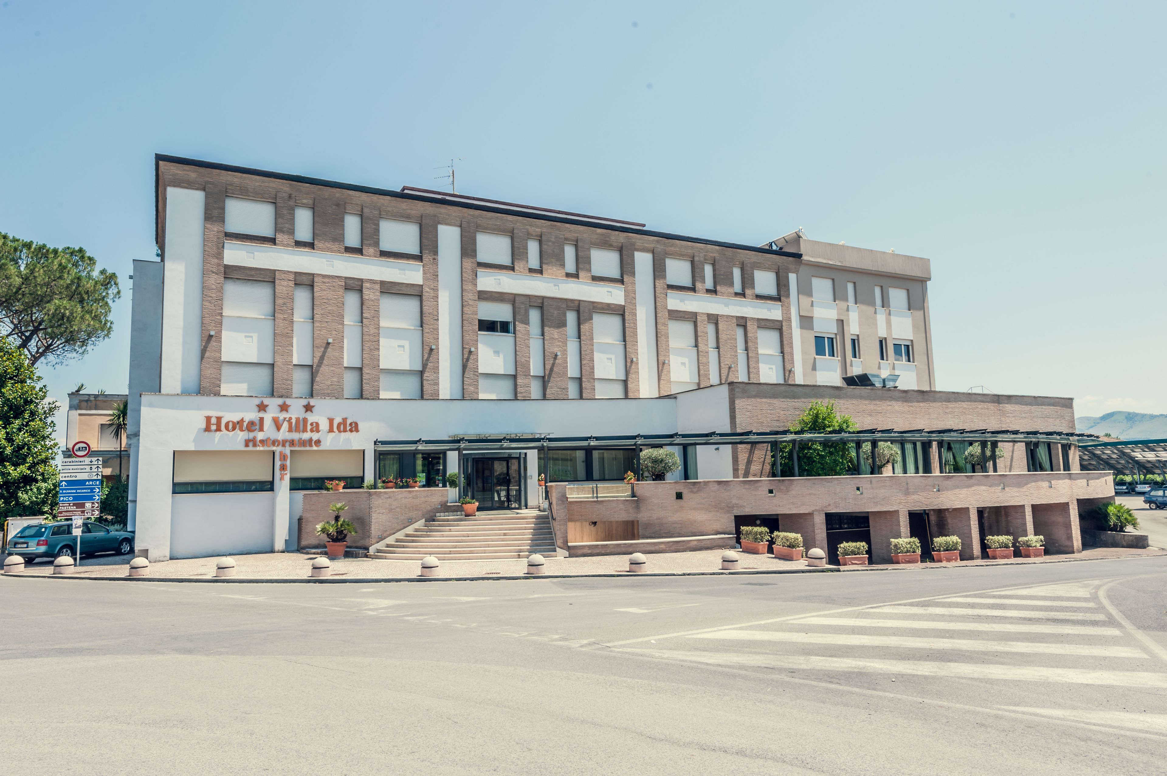 Un moderno edificio de hotel con techo plano, ventanas amplias y un letrero que dice "Hotel Villa Ida".
