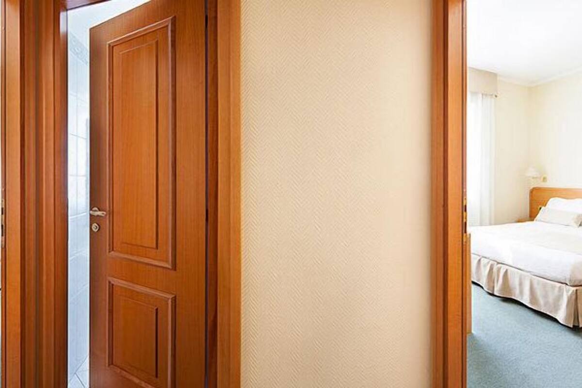 Une chambre d’hôtel avec deux lits, une porte en bois et une moquette de couleur claire.