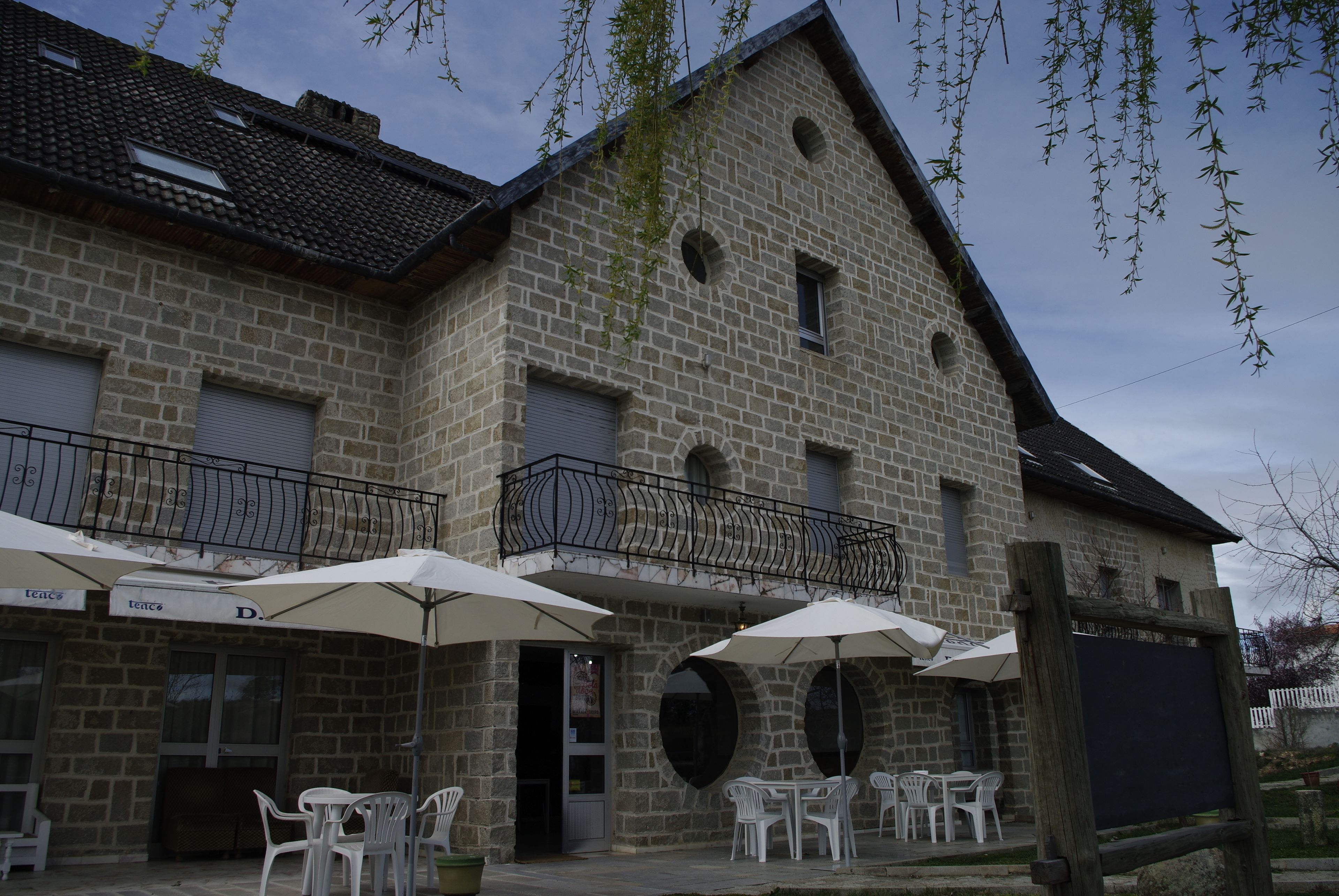 Un bâtiment en pierre doté d’une terrasse et de parasols.
