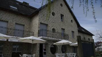 Un bâtiment en pierre doté d’une terrasse et de parasols.
