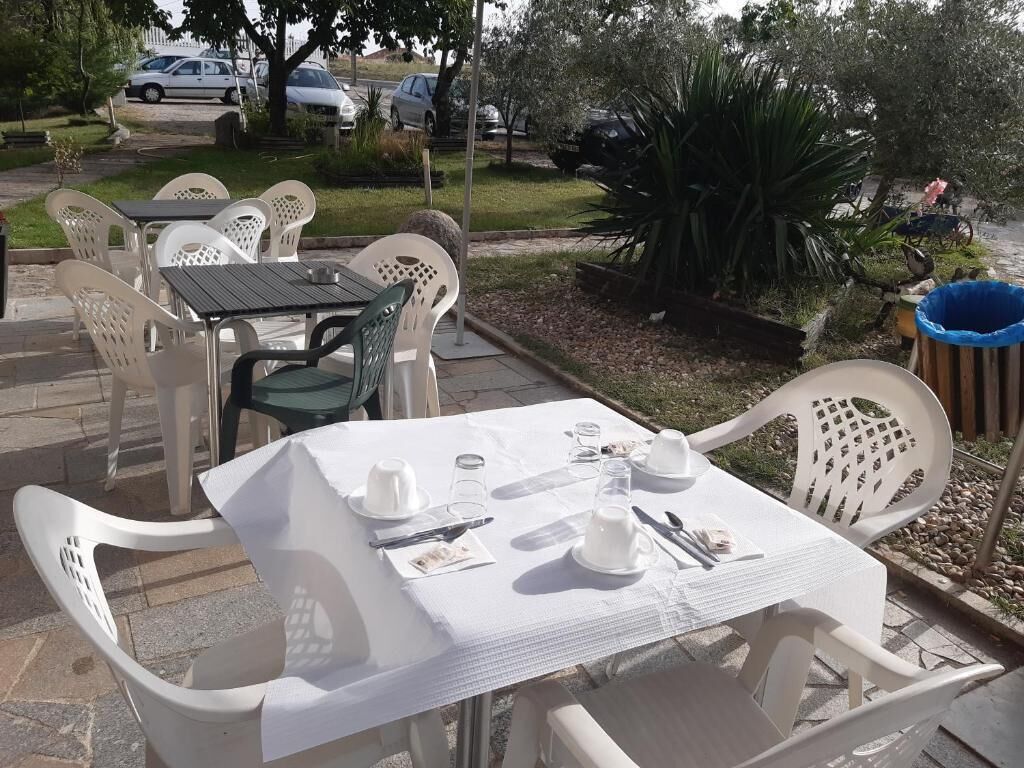 An outdoor dining area with white plastic chairs and tables, set up for a meal.