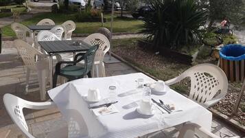 An outdoor dining area with white plastic chairs and tables, set up for a meal.