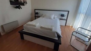 Una habitación de hotel moderna con una cama grande, mesitas de noche, lámparas de noche y una ventana con cortinas.