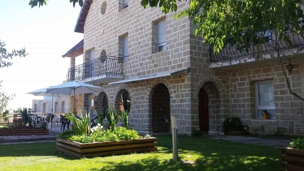 Un edificio de piedra con balcón, zona de estar al aire libre y jardín.