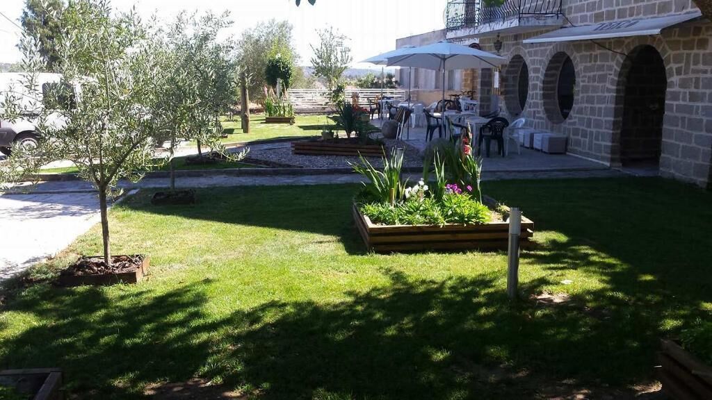 A courtyard with a small tree, flower beds, and outdoor seating.