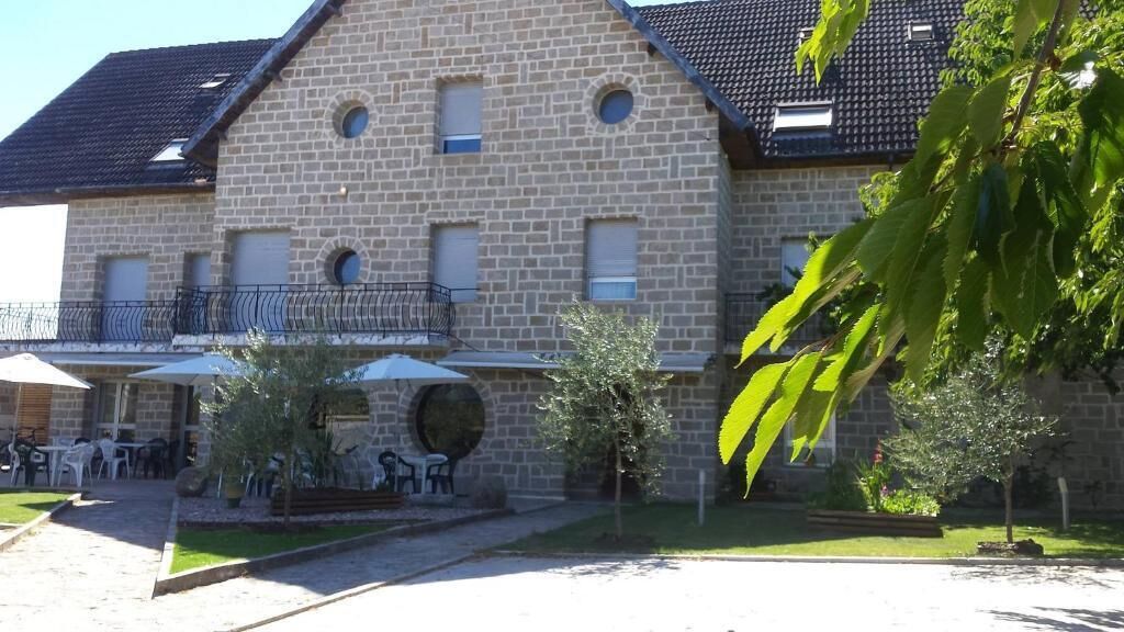 A stone building with a balcony, outdoor seating, and a small garden.