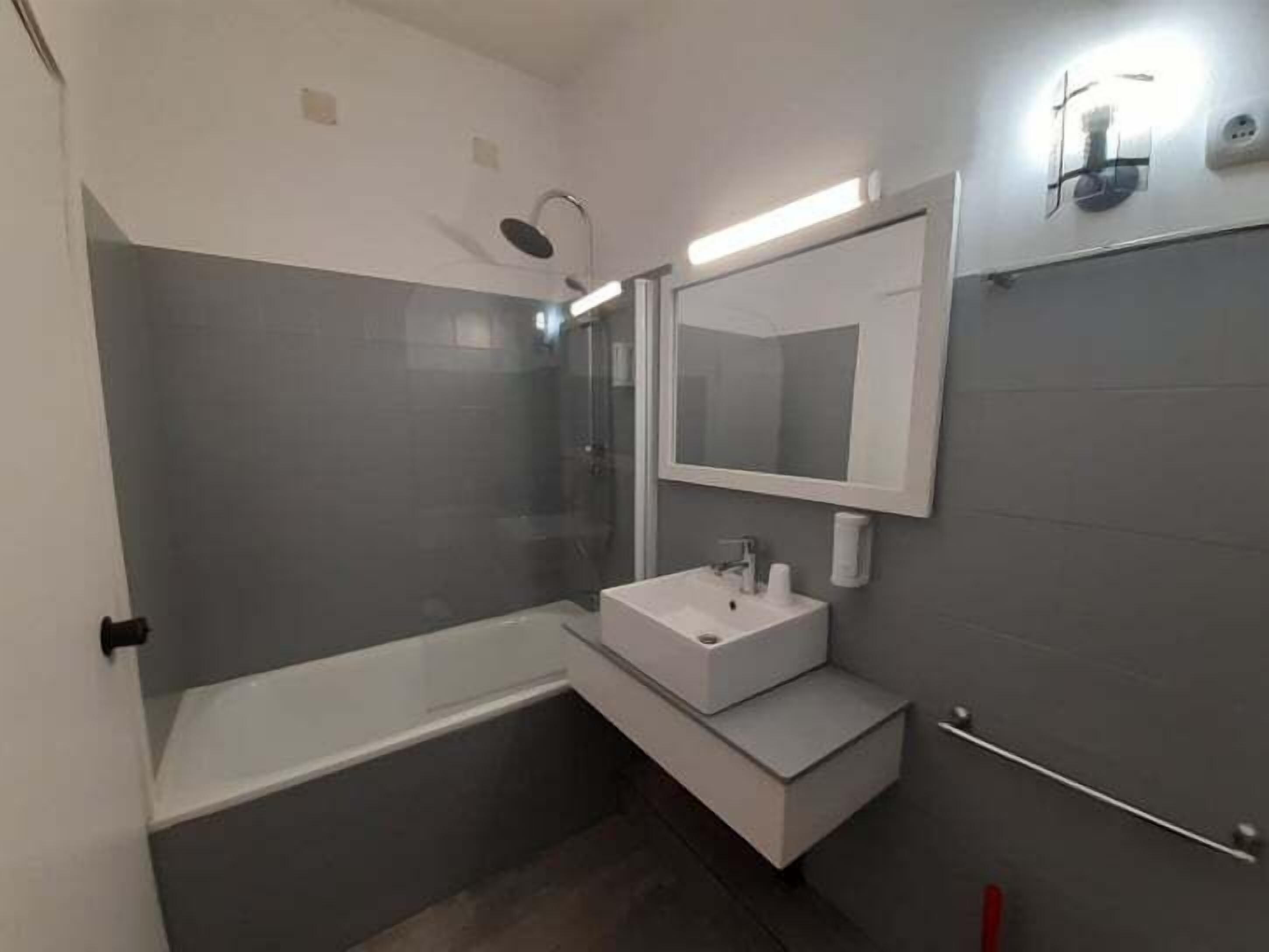 A modern bathroom with a bathtub, a sink, and a mirror.