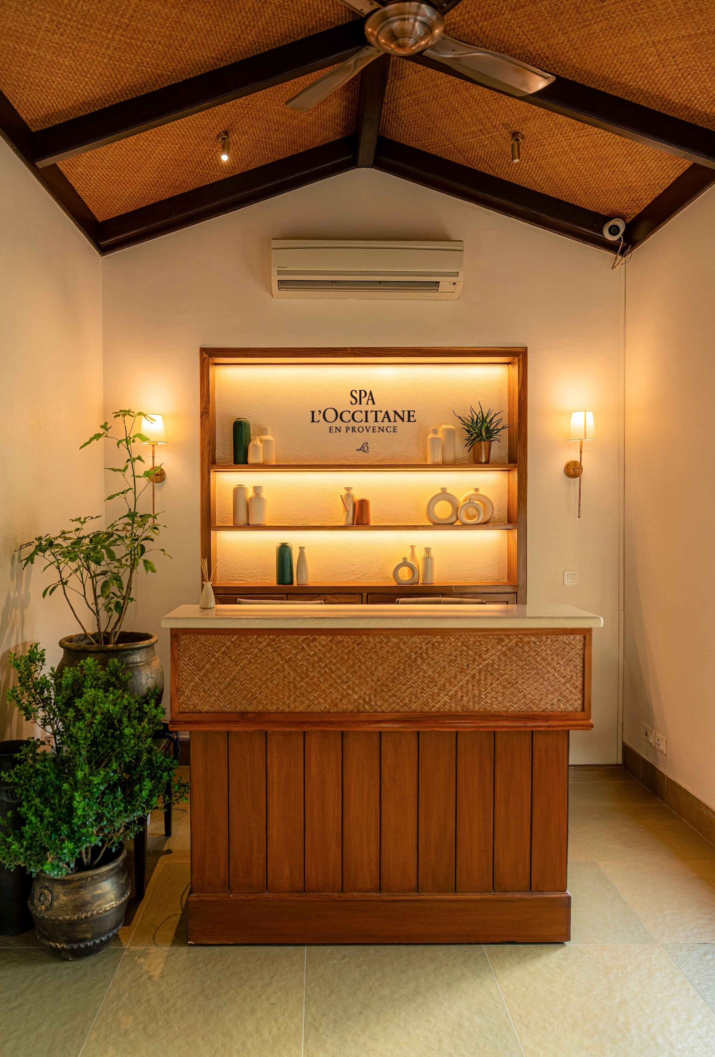 A reception desk with a wooden finish, a ceiling fan, and a wall-mounted air conditioner.