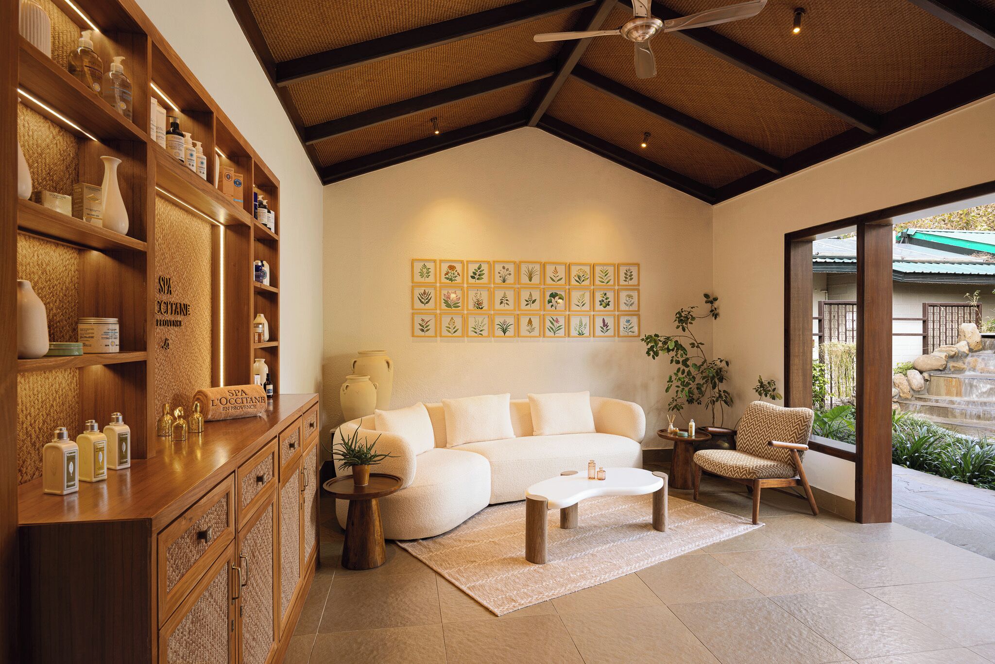 A modern living room with a sofa, coffee table, and wooden shelving with toiletries.