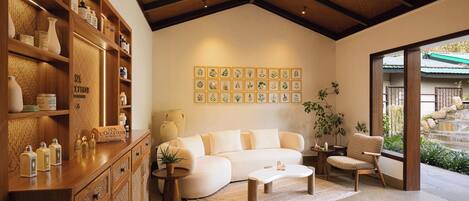 A modern living room with a sofa, coffee table, and wooden shelving with toiletries.