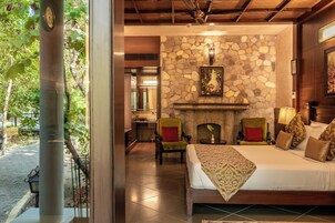 Un dormitorio con pared de piedra, chimenea y cama con colcha estampada.