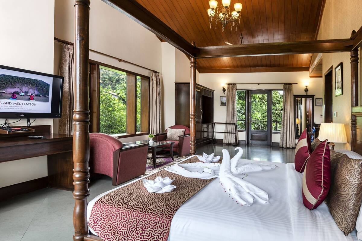 A hotel room with a bed, a desk, a television, and a view of the outdoors.