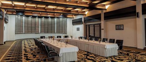 A conference room with a long table, chairs, and a patterned carpet.