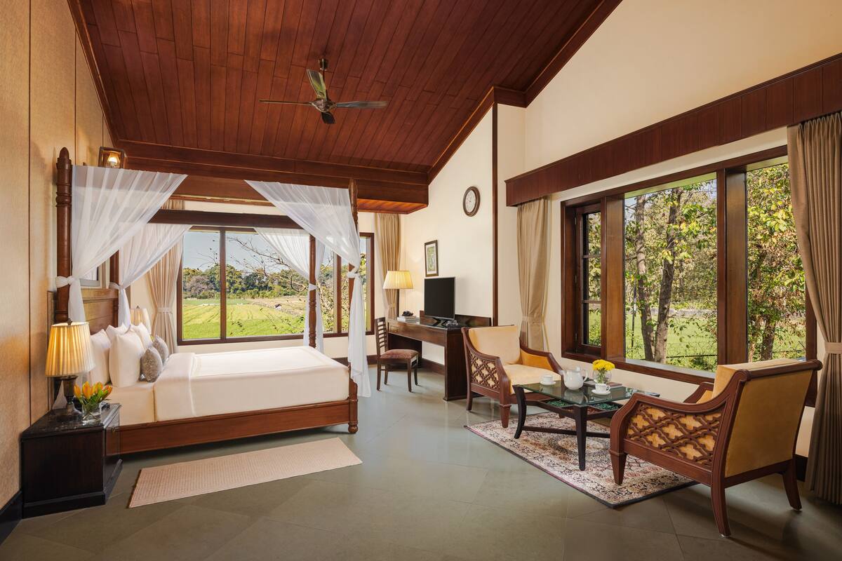 A bedroom with a bed, a desk, and a view of the outdoors.