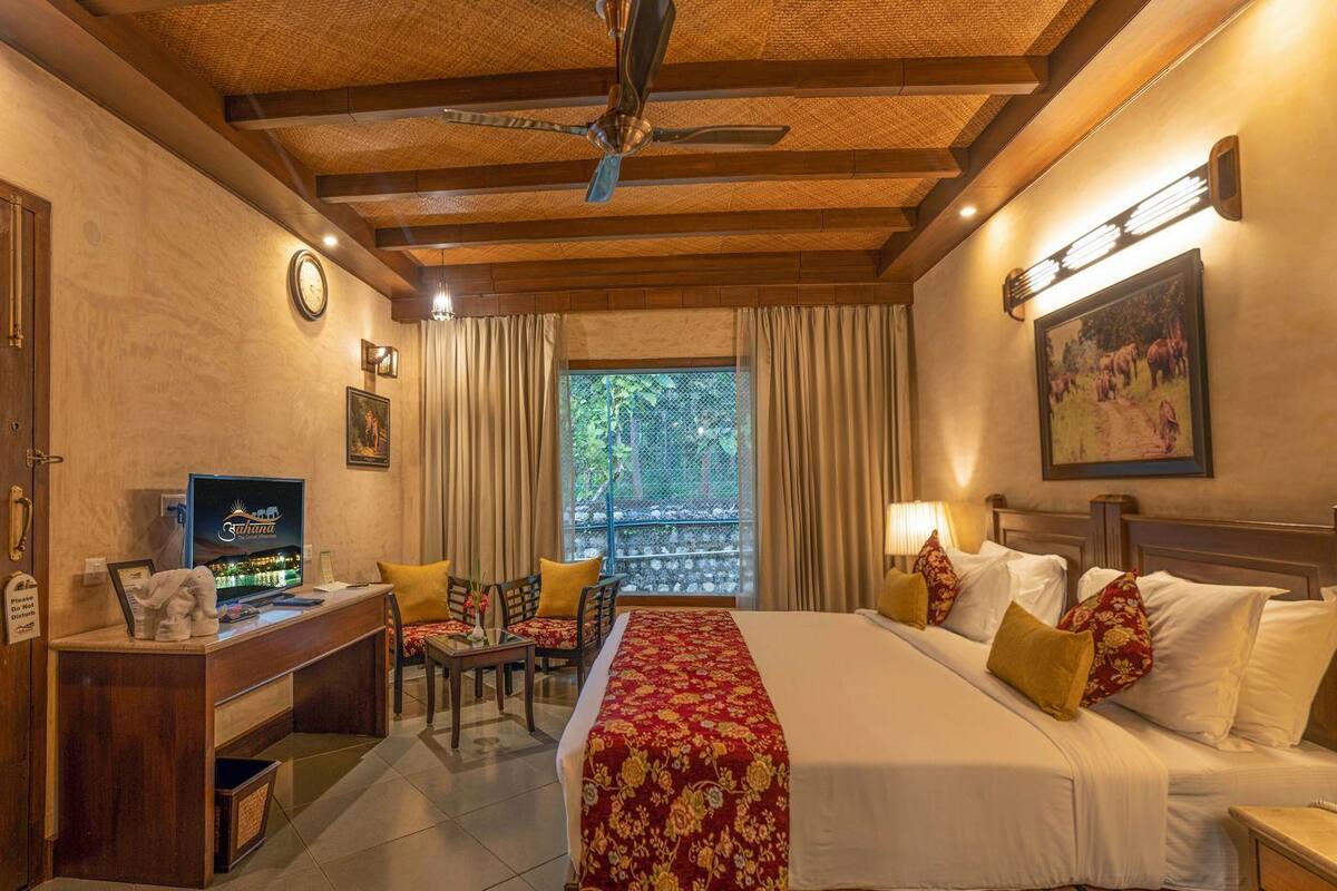 A hotel room with a bed, desk, chair, and a view of the outdoors.