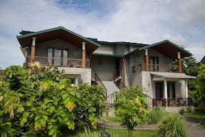 A two-story house with a stone facade, wooden balconies, and a staircase leading to the upper floor. - Aahana Resort & Spa - Jim Corbett (Ramnagar)