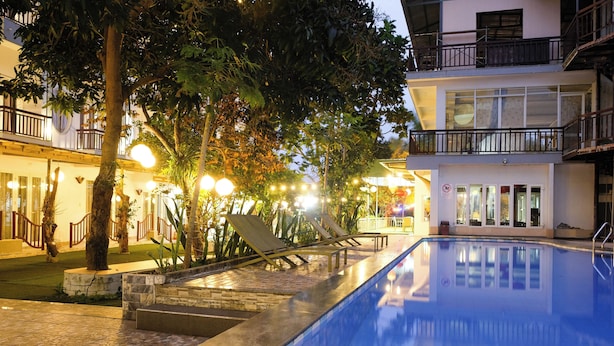 A swimming pool with lounge chairs and a well-lit outdoor area with trees and a building in the background. - Hoi An Paradise Hotel (Da Nang)