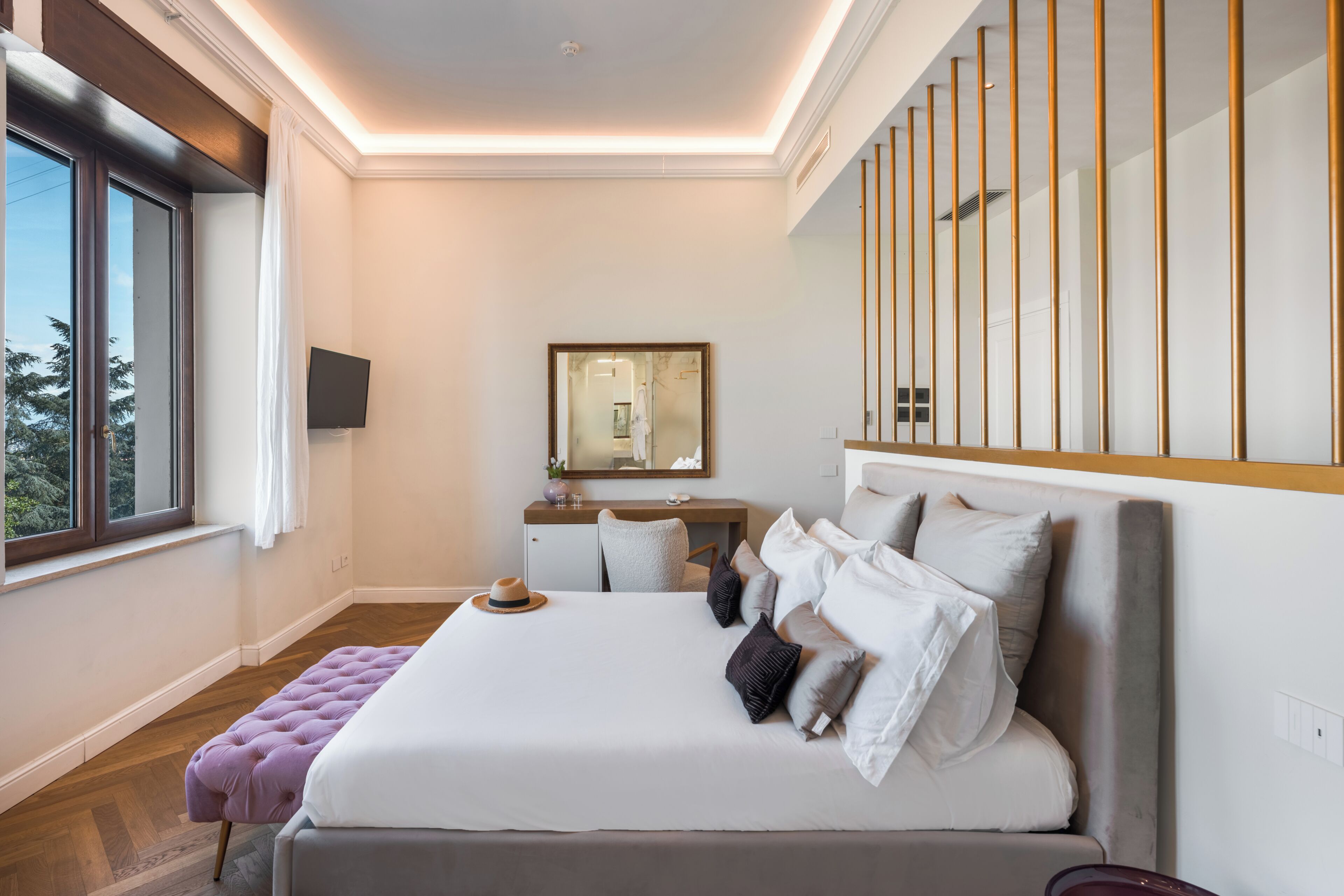 Une chambre moderne avec un grand lit, un bureau, une télévision et une fenêtre avec des rideaux.