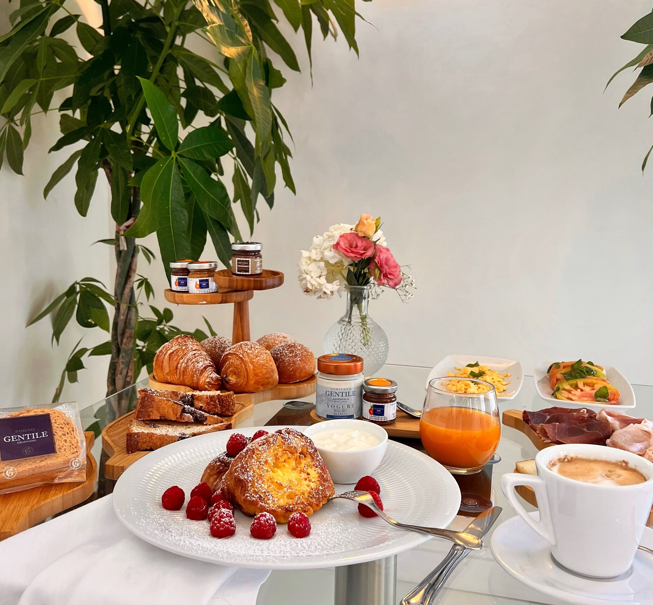 A breakfast setting with pastries, jams, yogurt, and a variety of fruits and meats.