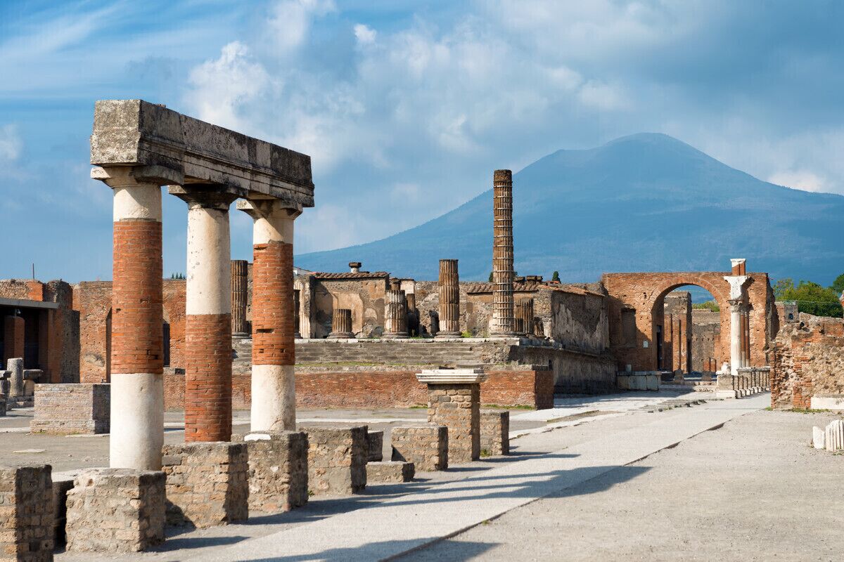 Rovine antiche con colonne e una montagna sullo sfondo.