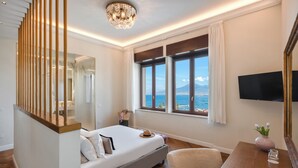 Ein Hotelzimmer mit Bett, Schreibtisch, Stuhl, Fernseher und Fenster mit Meerblick.