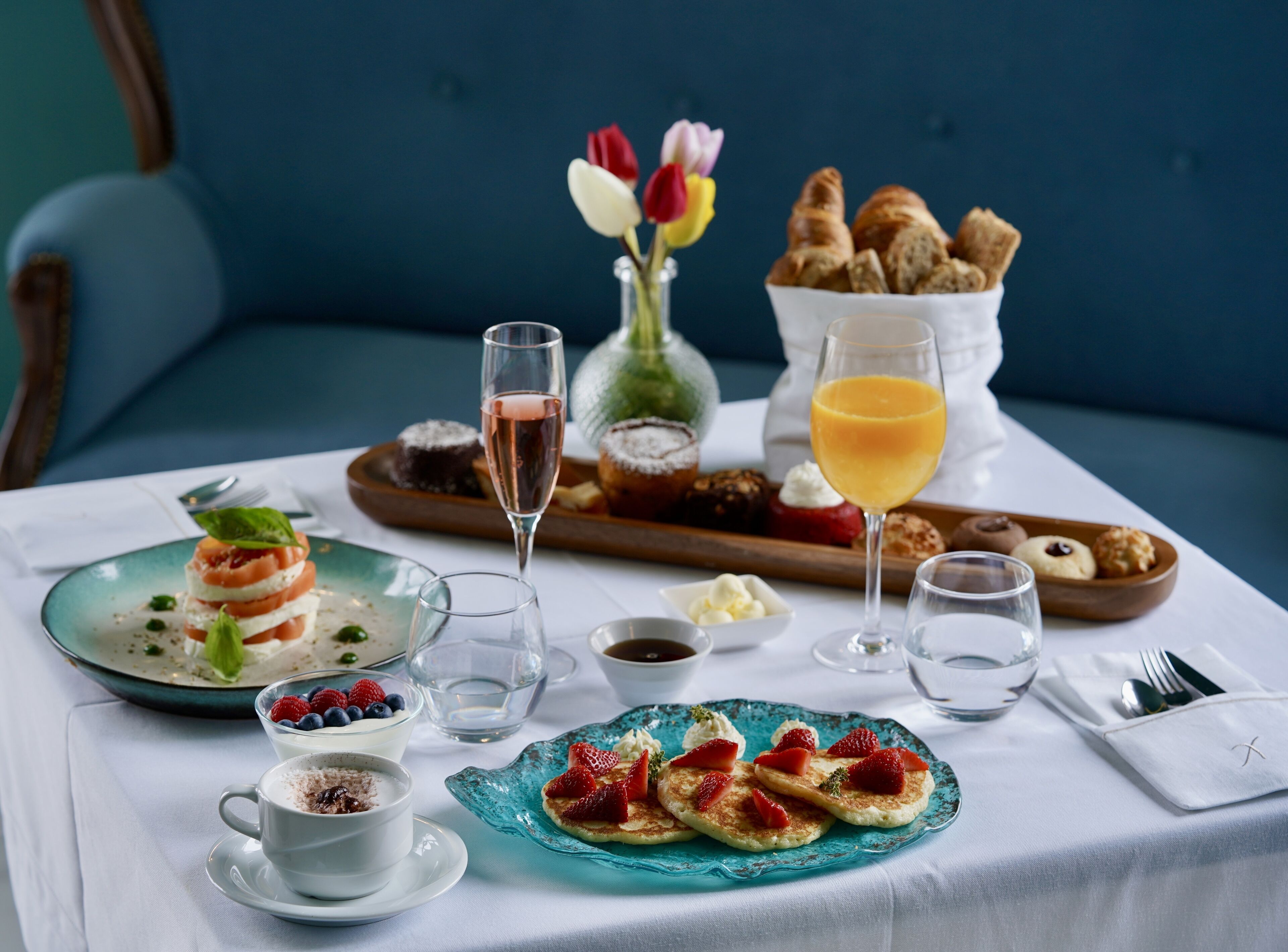 A breakfast setting with various dishes, drinks, and a vase of flowers.