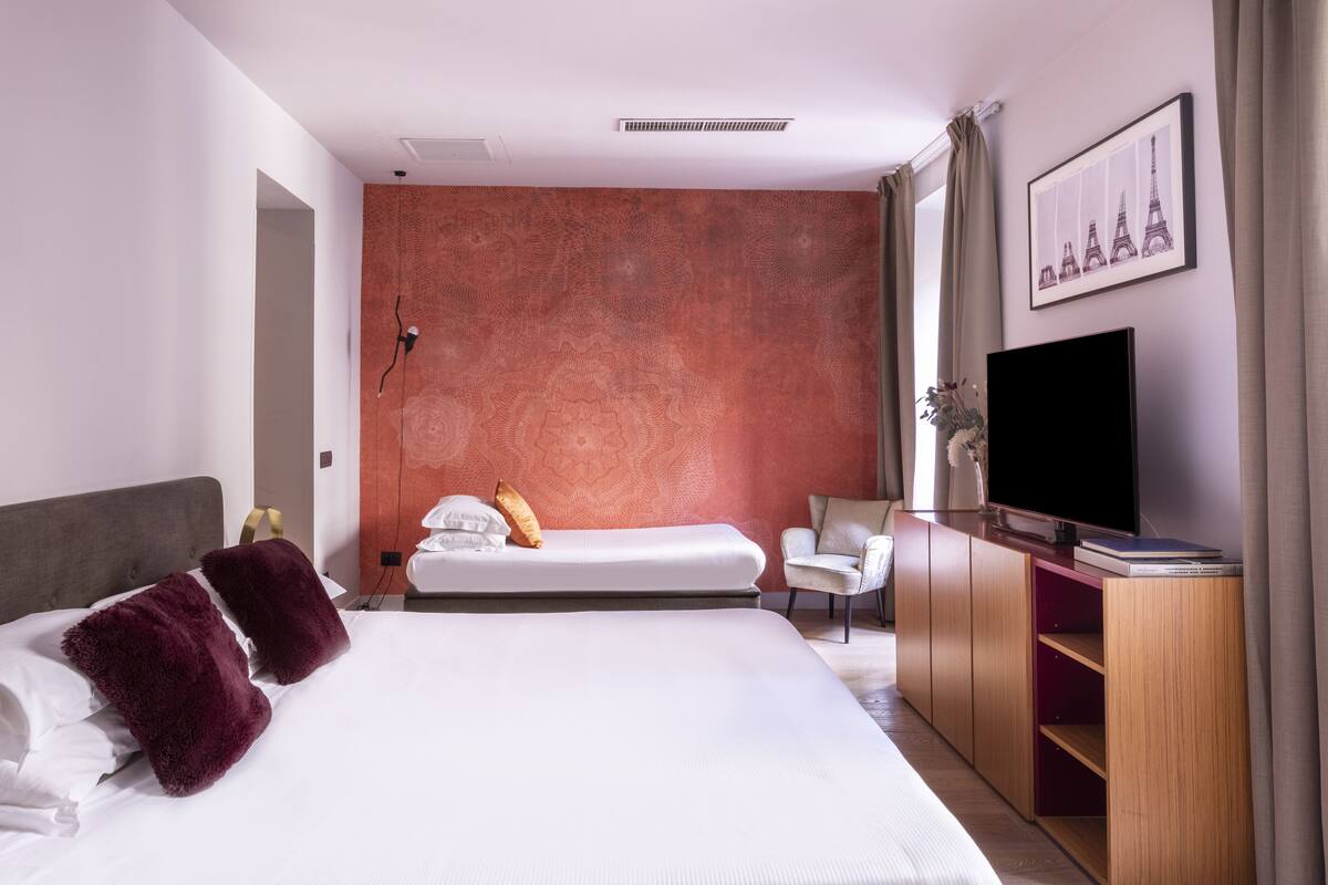 A hotel room with a large bed, a TV, a chair, and a wall with a picture of the Eiffel Tower.