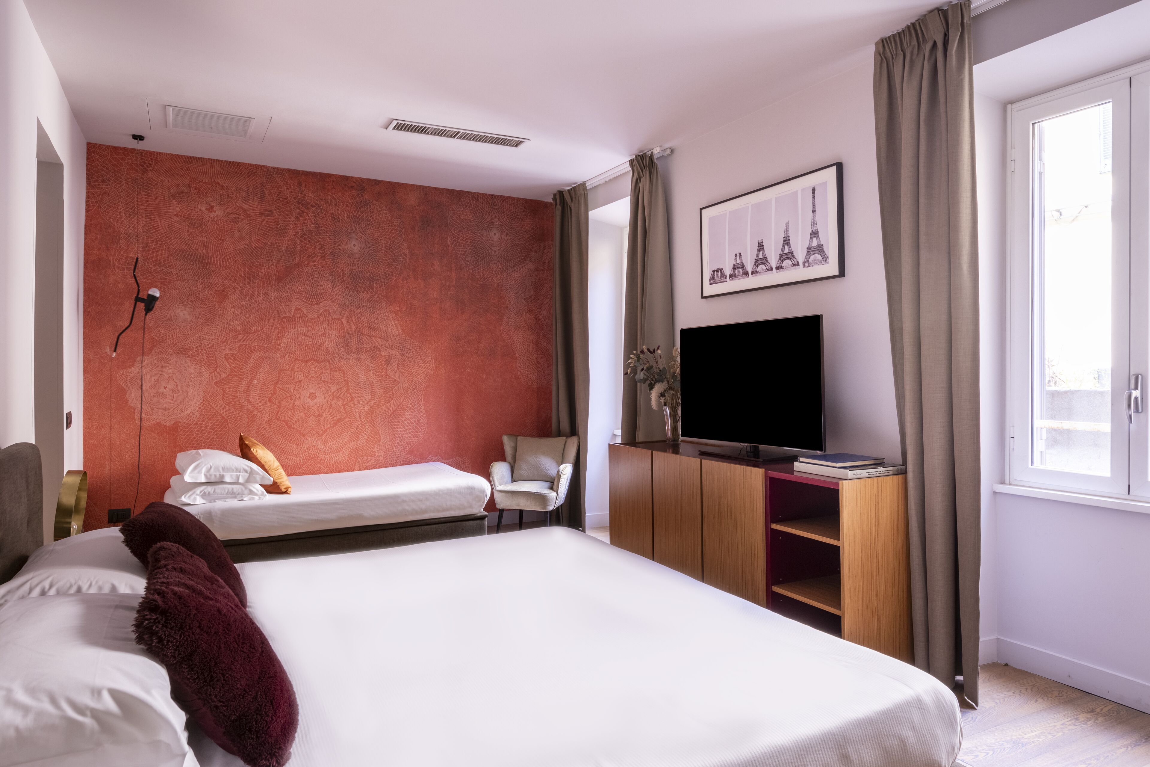 Una habitación de hotel con una cama grande, un escritorio con una computadora, una silla, un televisor y una ventana con cortinas.