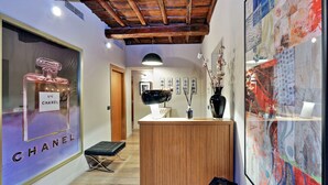 Un interior moderno con un mostrador de recepción de madera, un cuadro abstracto grande y el escaparate de una tienda Chanel.
