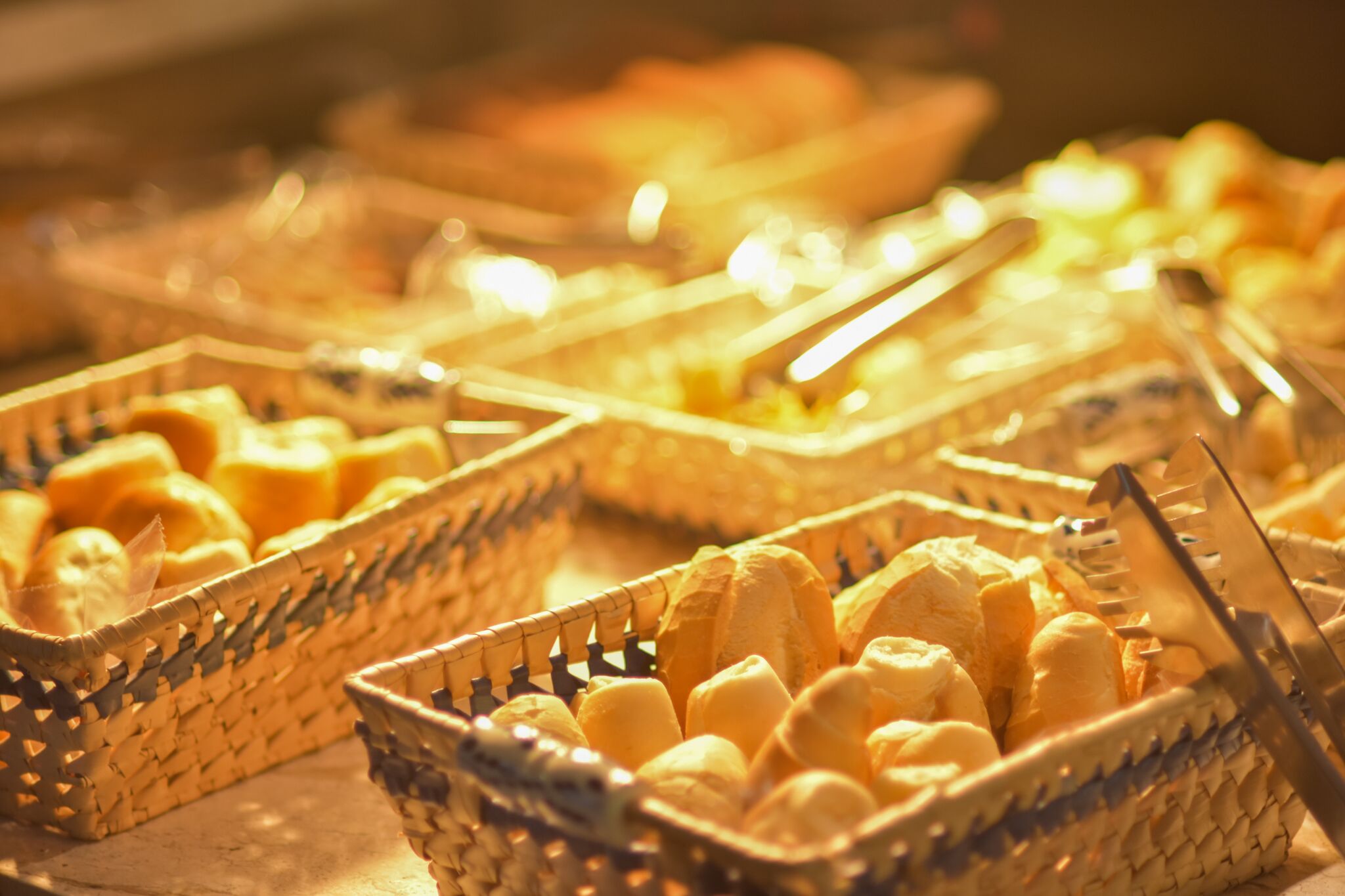 A buffet with baskets of bread and utensils.