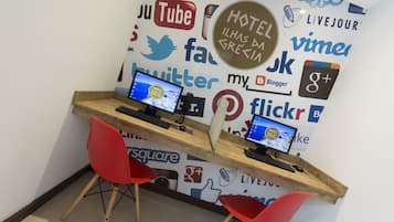 A workspace with two computers, a red chair, and a wall decorated with various social media and technology logos.