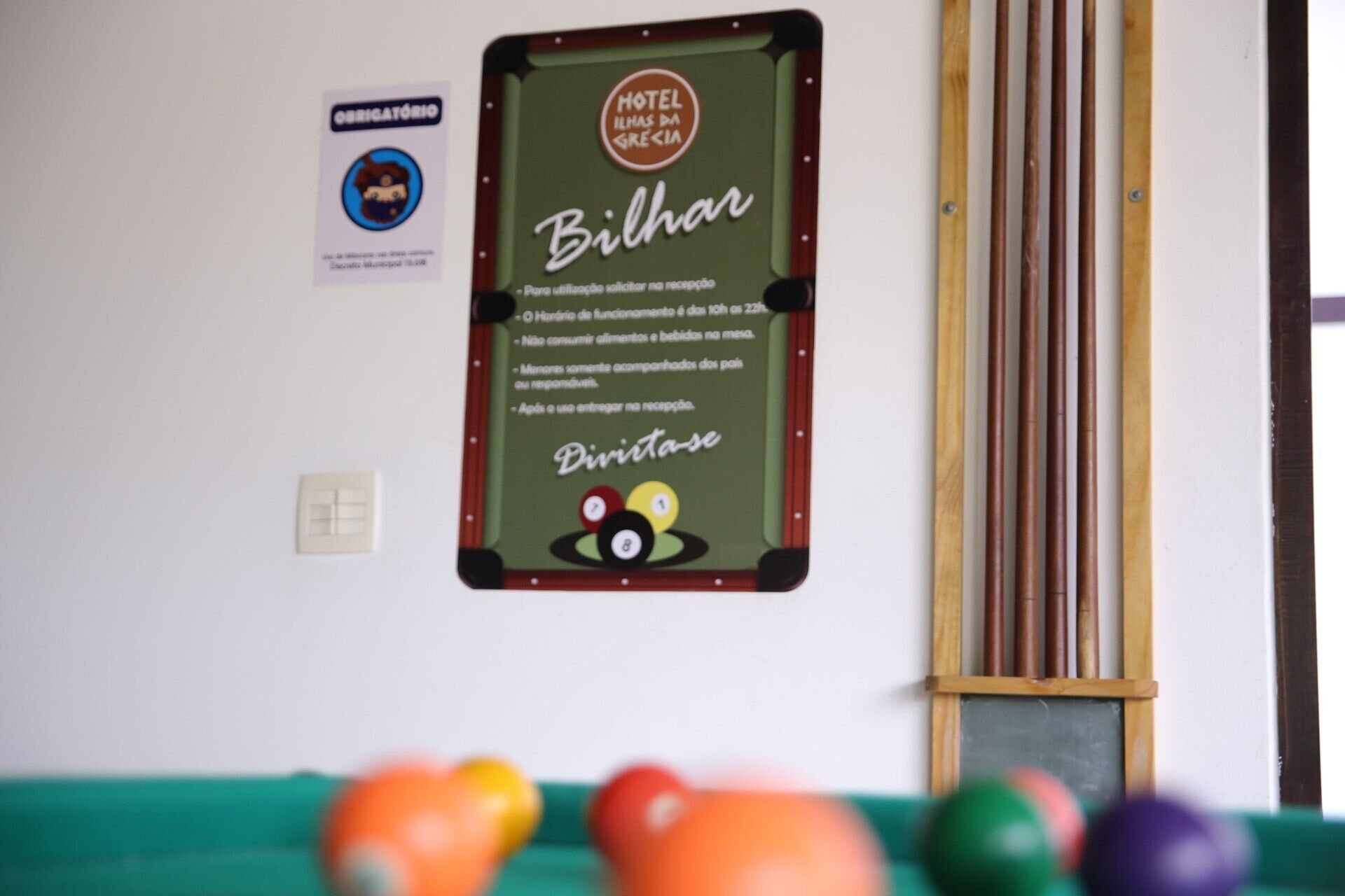 Une table de billard avec un panneau indiquant les règles et le logo de l’hôtel « Ilhas da Grecia ».
