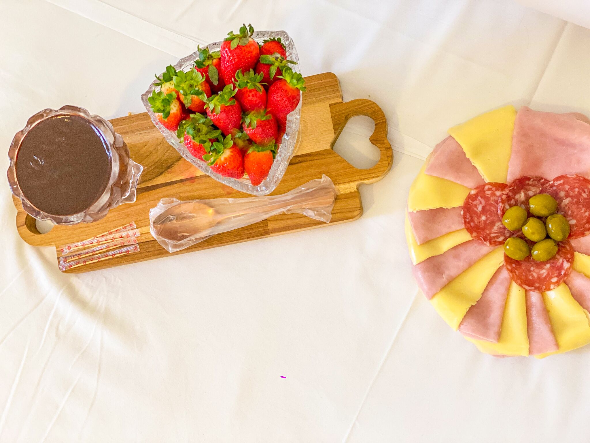 A tray with strawberries, a chocolate dish, and a meat and cheese arrangement.
