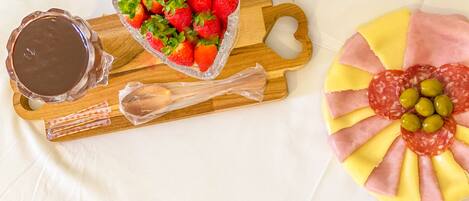 A tray with strawberries, a chocolate dish, and a meat and cheese arrangement.