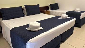 A hotel room with two beds, each with a white pillow and a blue headboard.