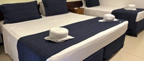 Habitación de hotel con dos camas, cada una con almohada blanca y cabecero azul.