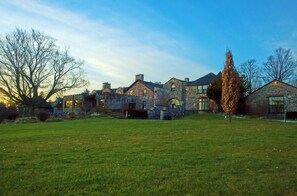 A stone building with multiple chimneys and a grassy lawn.