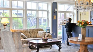 A spacious room with a large window, a sofa, a coffee table, and a chandelier. - Ste. Anne's Spa (Alnwick/Haldimand)