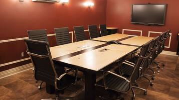 A conference room with a long table, black chairs, and a flat-screen TV on the wall.