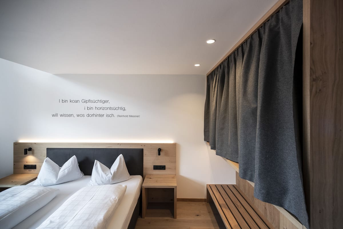 A modern bedroom with a bed, bedside tables, and a wall-mounted shelf.