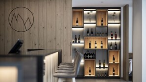 Un espace bar moderne avec un mur en bois et des étagères où sont exposées différentes bouteilles.