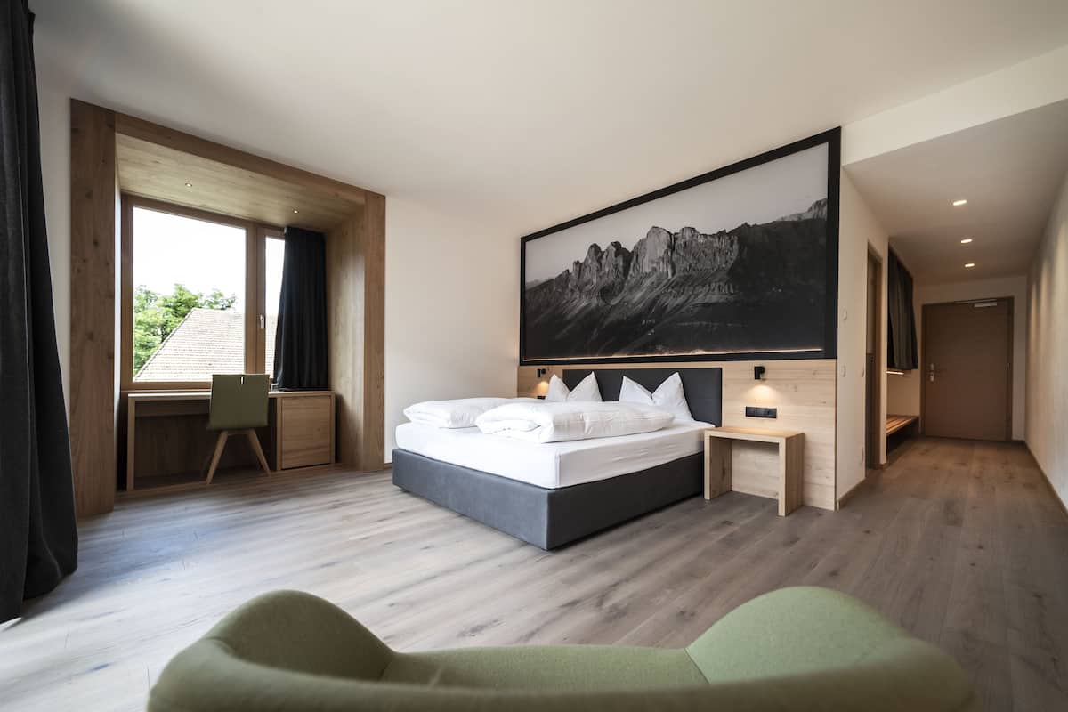 A modern bedroom with a large bed, a desk, and a chair.